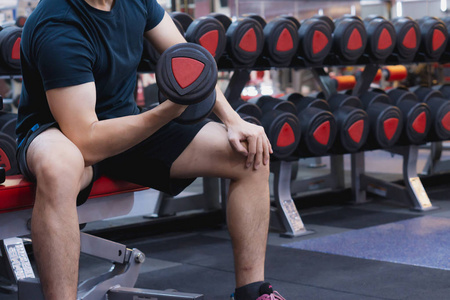 Young sporty man doing dumbbell curl in gym. Sport and exercise 