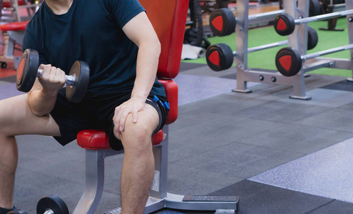 Young sporty man doing dumbbell curl in gym. Sport and exercise 