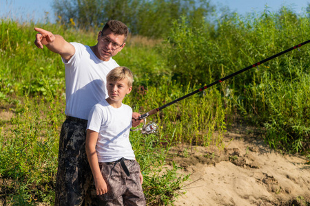 父子俩一起在湖边钓鱼。