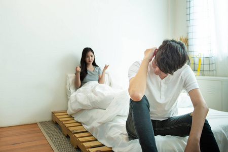 亚洲男人抑郁和感情不好的女人吵架后坐在床上，夫妻生活中的社会问题。