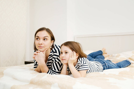 Young mother and her daughter child lying on bed in bedroom and 