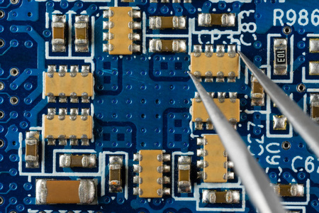 用镊子焊接在蓝色电子板上安装或拆卸电子元件