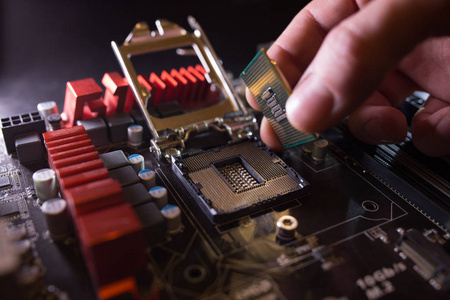 技师将CPU微处理器插入主板插座。研讨会背景。PC升级或维修概念。