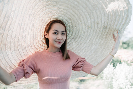 美丽的亚洲女人她喜欢在花园里戴着大帽子