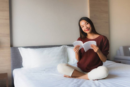 美丽的亚洲年轻女性在床上看书