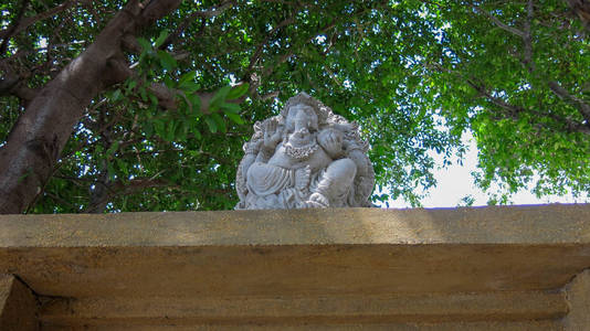 Yellow brick gate with white stone statue of Hindu God Ganesha. 