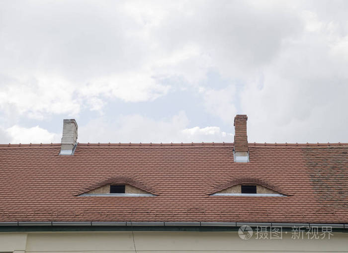 两个带窗户的老虎窗在修好的棕色陶瓷屋顶上
