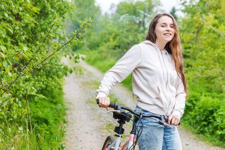 年轻女子骑自行车在夏季城市公园户外。活跃的人。时髦女孩放松和骑自行车