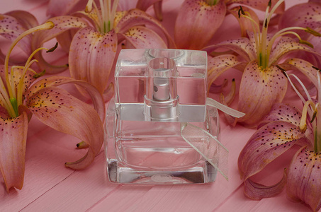 香水，马桶水，一个透明的瓶子，粉红色的背景是粉色的百合花。为化妆品做广告。水平照片