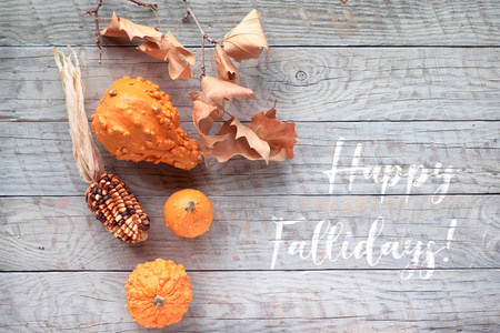 Autumn leaves and pumpkins, text Happy Holidays. Flat lay, top