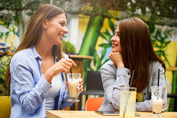 两个女朋友在咖啡厅聊天，玩得很开心