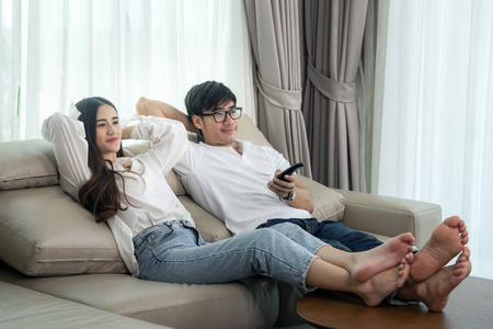 一对亚洲夫妇在沙发上睡觉放松看电视照片