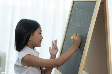 亚洲女孩背t前在篮板上写字和做家庭作业