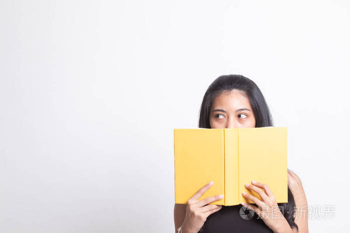 一位年轻的亚洲妇女拿着一本书遮住了她的脸