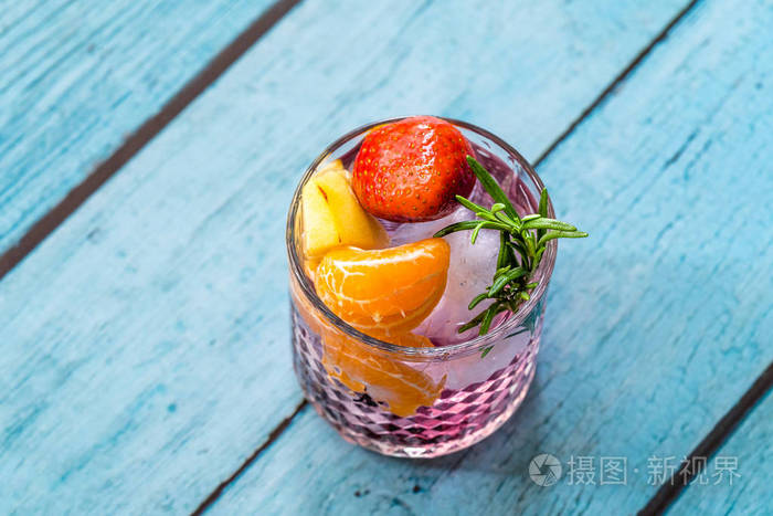 水果鸡尾酒配草莓柑橘苹果和迷迭香新鲜粉红色饮料。夏季饮料。
