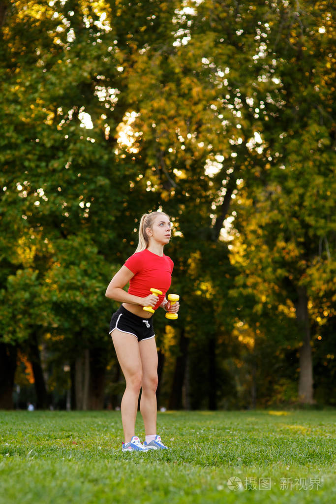 一个小女孩喜欢用哑铃做运动健身妇女在公园户外锻炼