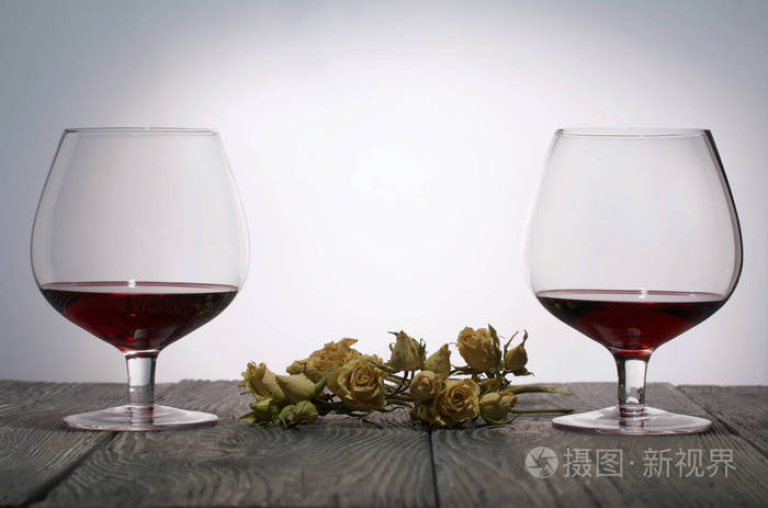 红酒杯一束干玫瑰站在木板上背光拍摄