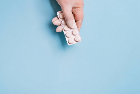 一个医生手拿药片的特写镜头,蓝色背景照片