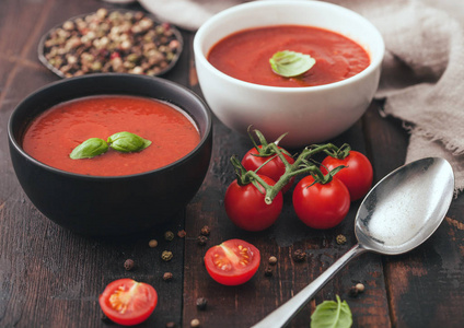 奶油番茄汤陶瓷碗盘，配汤匙胡椒粉和厨房布，背景为生番茄。