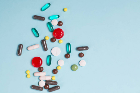 蓝色背景上的不同颜色的药丸和药片。