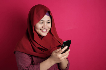 在智能手机上读短信时微笑的穆斯林妇女