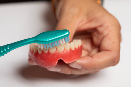 用牙刷清洁义齿或牙齿修复体的特写镜头