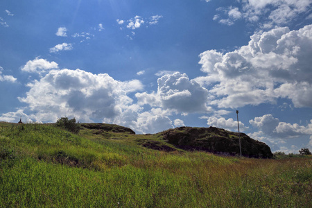 夏季景观。在蓝天白云的衬托下，山坡上有野草的草地。