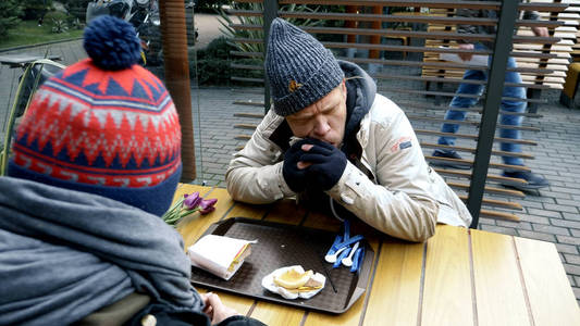 一对无家可归的夫妇，一男一女在街边咖啡馆吃剩的东西