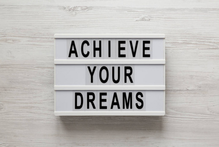 Achieve your dreams words on a modern board on a white wooden 