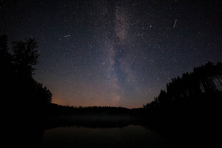 夜晚湖面上有一百万颗星星。长期暴露。飞行卫星的踪迹。银河系