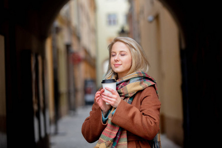 Blonde woman with cup of coffee in old town 