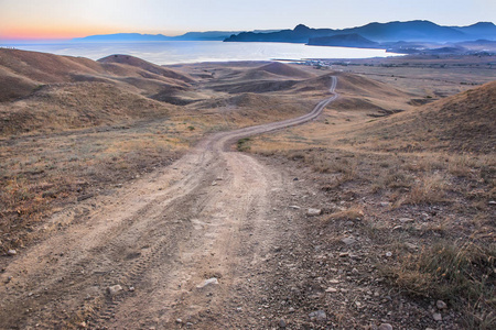 Landscape dirt road over the hills to the sea 