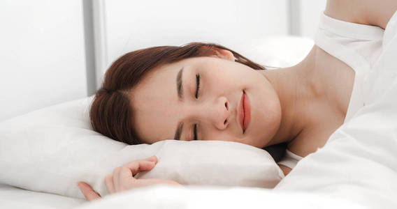 熟睡中的年轻亚洲女人躺在床上享受放松
