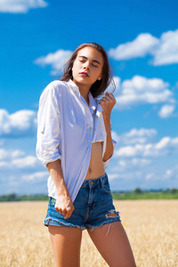 Young brunette woman in white shirt and blue jeans shorts 