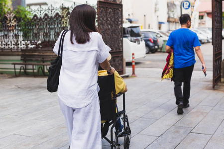 Daughter taking her mother on wheelchair for side seeing a small