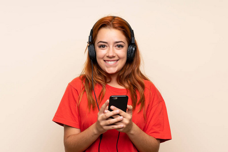 十几岁的红发女孩在孤独的背景下用手机听音乐