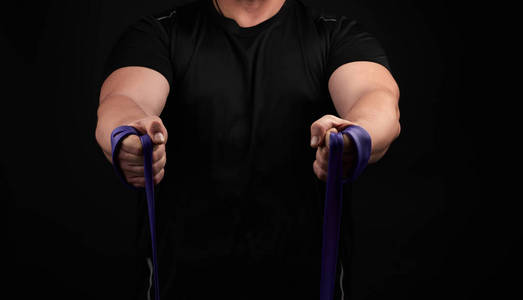 athlete with a muscular body in black clothes is doing physical 