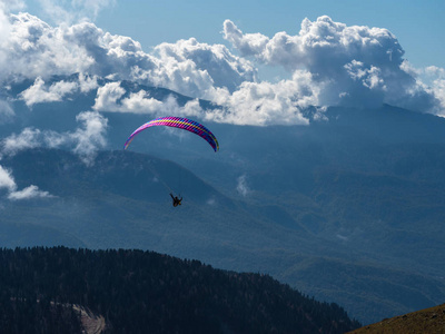 滑翔伞飞越云层，飞越群山和森林