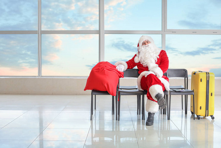 带着行李的圣诞老人在机场等他的航班。度假的概念