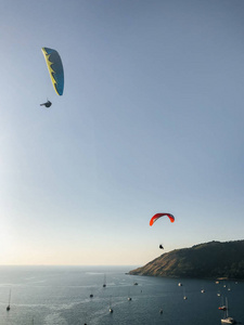 Skydivers fly over the sea against the backdrop of a beautiful s