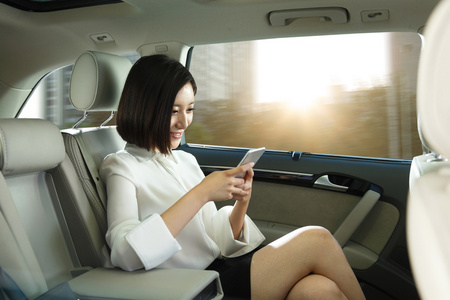 青年女人坐在汽车里看手机 照片