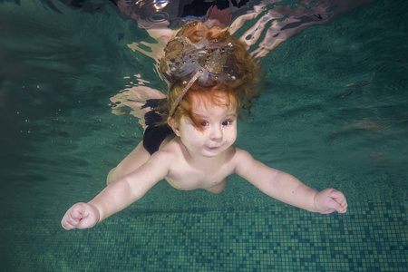 红头发的小女孩学会了在水下游泳.婴儿游泳和照片
