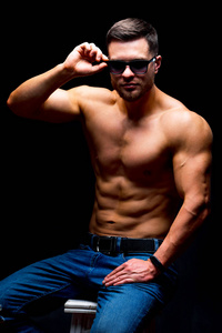 一个肌肉发达，肌肉发达的男子在黑色背景上摆姿势的肖像。