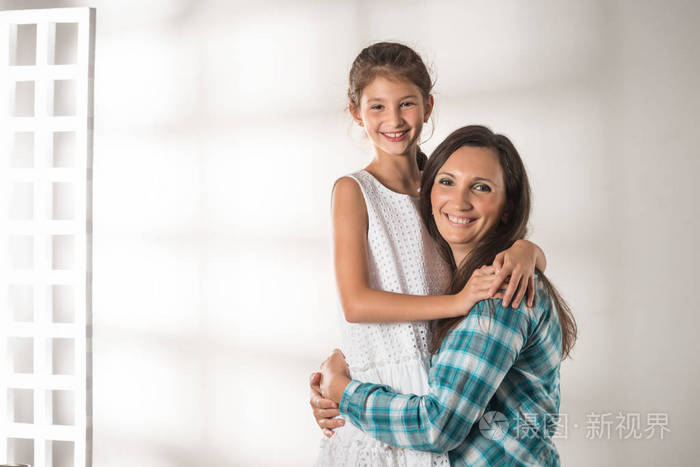 年轻的母亲抱着她非常积极的女儿