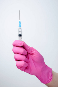 手拿注射器，戴着医用粉色手套。注射疫苗。医学