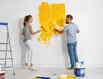 这对幸福的年轻夫妇正在坎修墙和粉刷墙