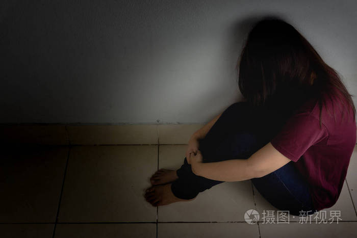 一个悲伤的女人独自坐在黑暗的房间里哭泣dep公司