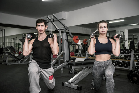 男女双人在健身房训练上角拍摄笑脸盈盈的女运动员,女运动员穿着运动