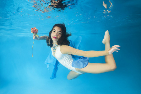 年轻漂亮的女孩穿着一件连衣裙，在游泳池里摆着花