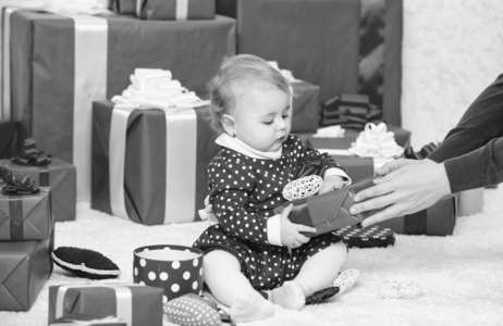 婴儿第一个圣诞节一次一生中的事件。小宝宝在一堆包装好的红色礼盒旁玩耍。儿童第一个圣诞节礼物。我的第一个圣诞节。与家人分享宝宝第一